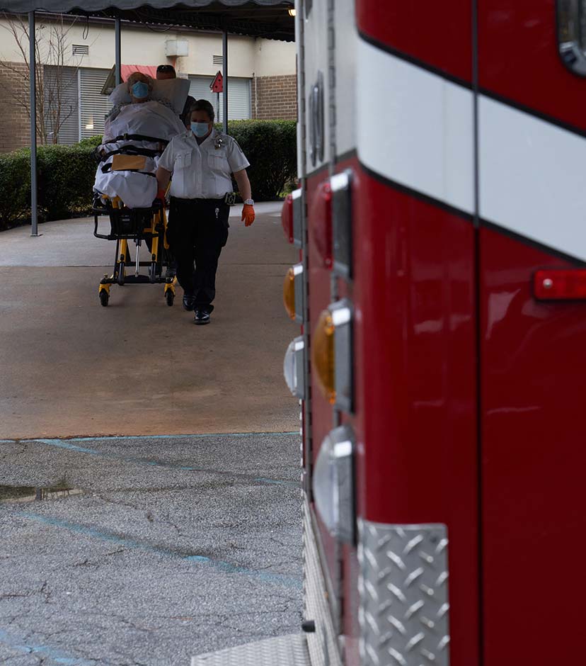 EMTs wheeling a patient down a ramp.