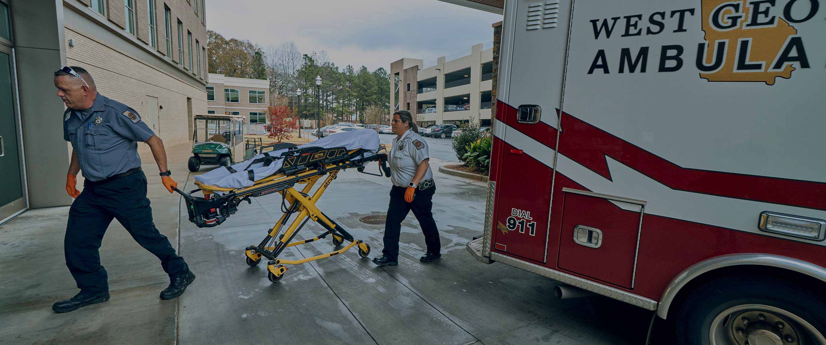 EMTs entering a building with an empty stretcher.
